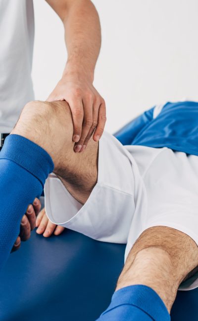 Physiotherapist massaging leg of football player in hospital